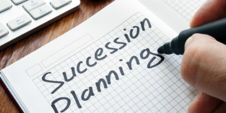 person writing the words, succession planning, on paper